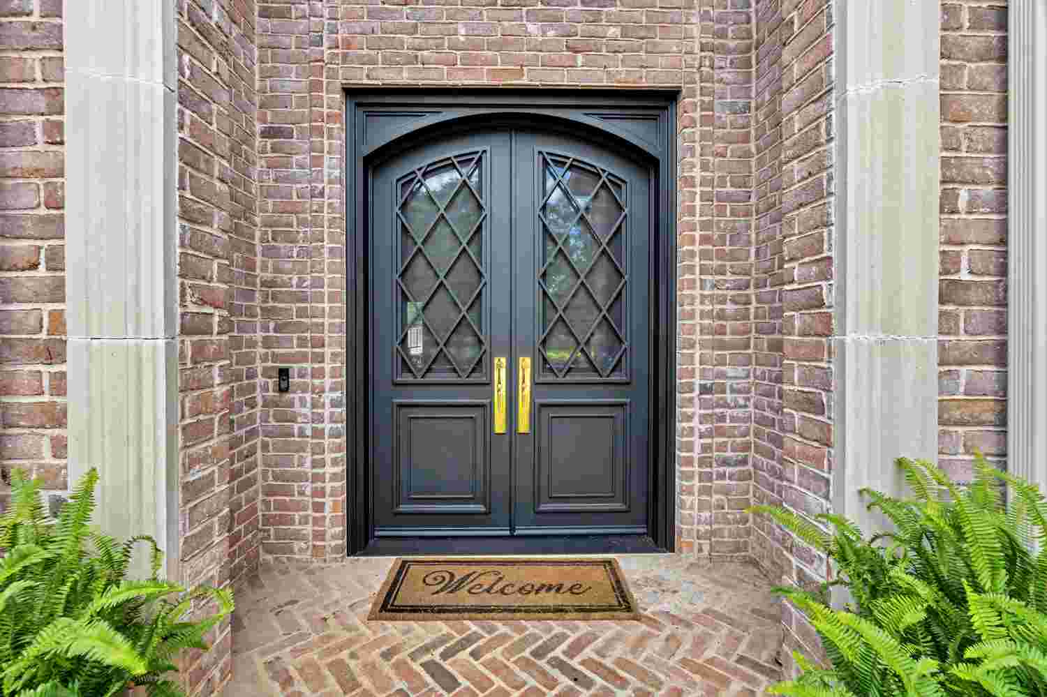 Steel double door with arched top, black finish, clear glass, and diamond grille