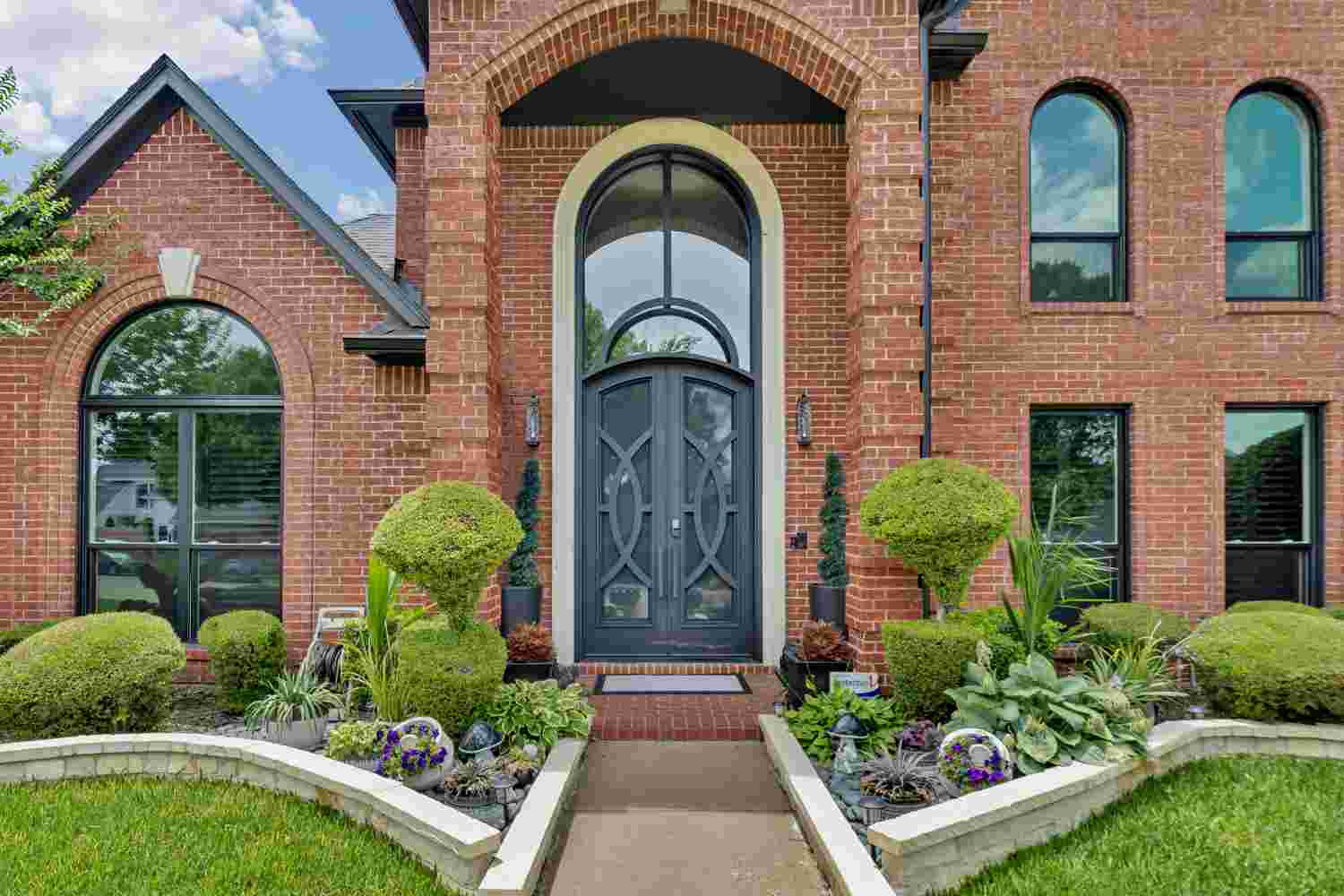 Traditional arched steel double door with transom window and scrollwork