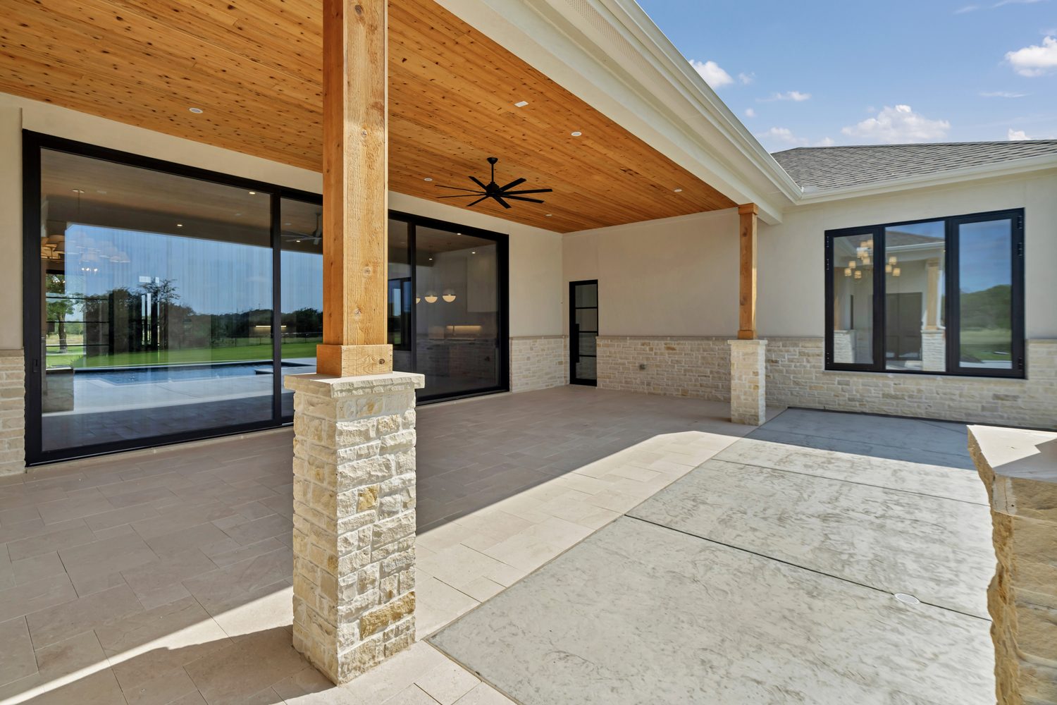 Covered porch outdoor living space with glass windows and stone columns