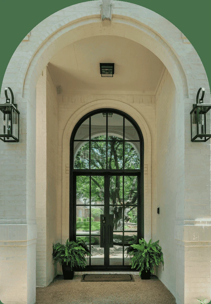 Arched black framed glass entry with lanterns and ferns - Love That Door