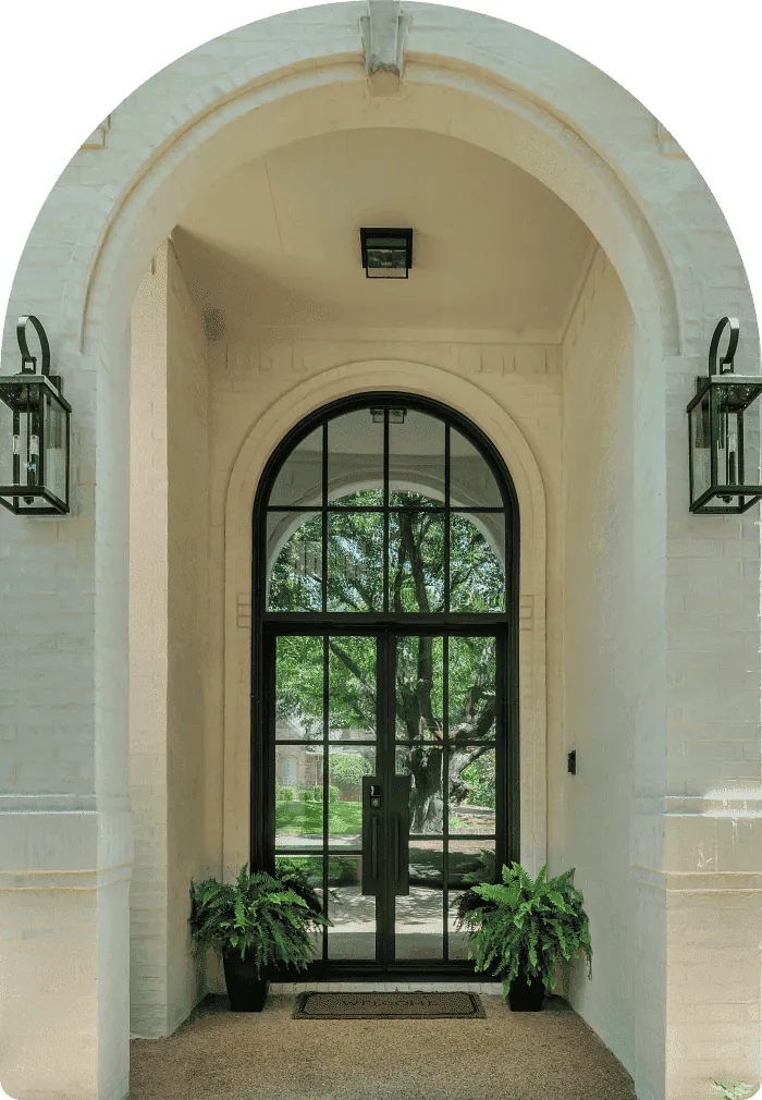 Arched black-framed glass entry door flanked by lanterns and potted ferns - Love That Door