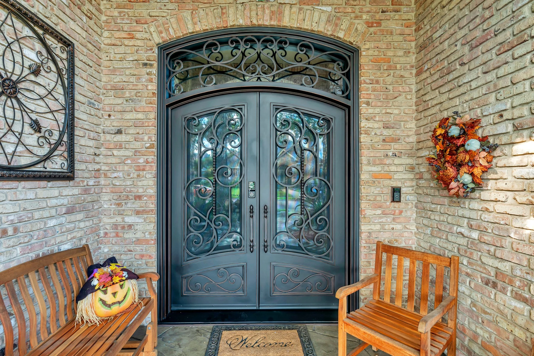 Black steel double arched entry door with scrollwork, sidelights and transom