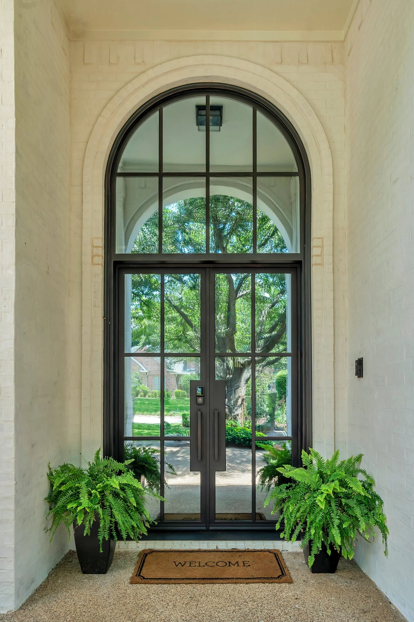 Black steel double arched entry door with sidelights, brick exterior