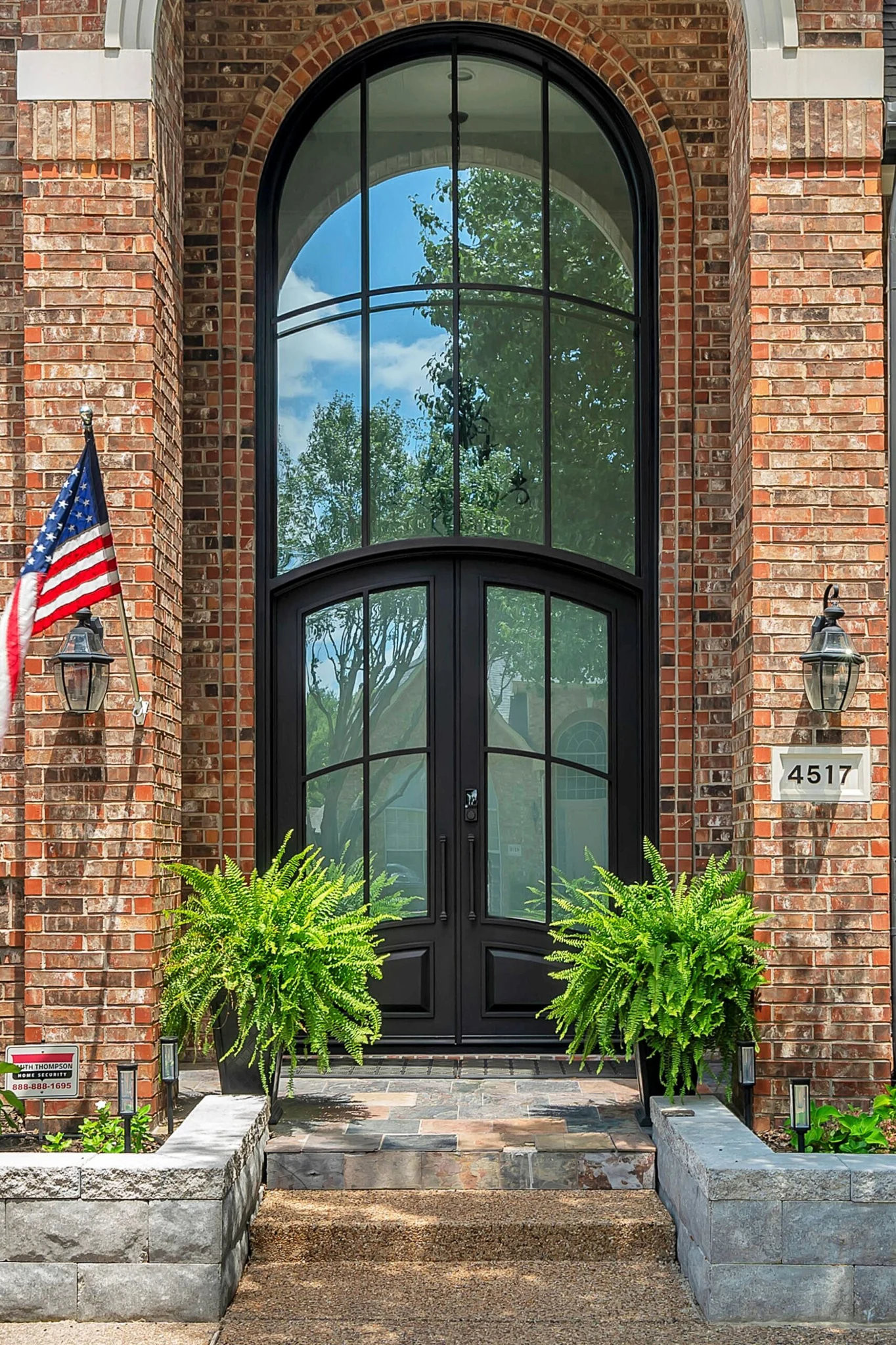 Black steel double arched entry door with sidelights and transom, brick