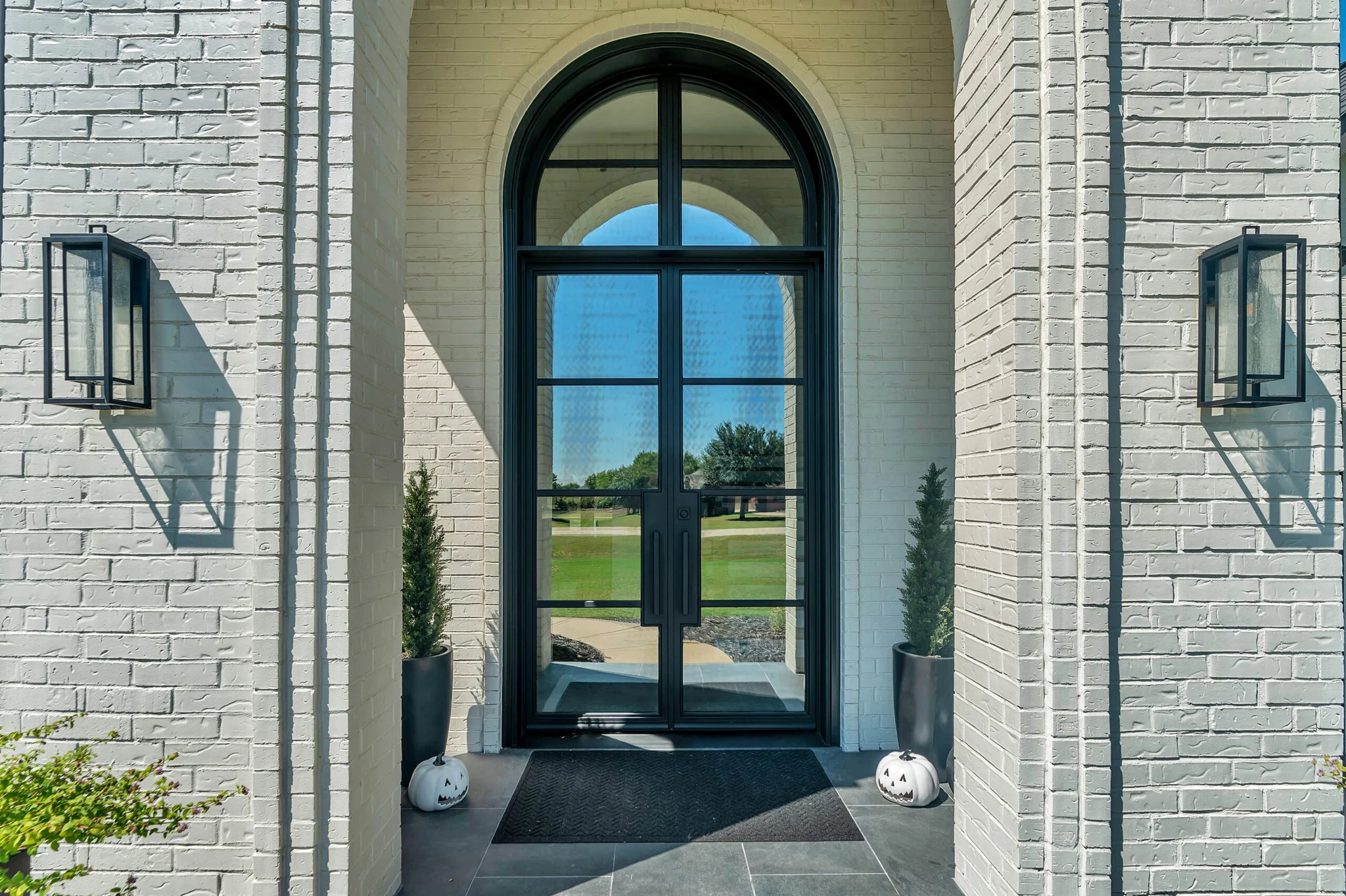 Black steel double arched entry door with sidelights, white brick