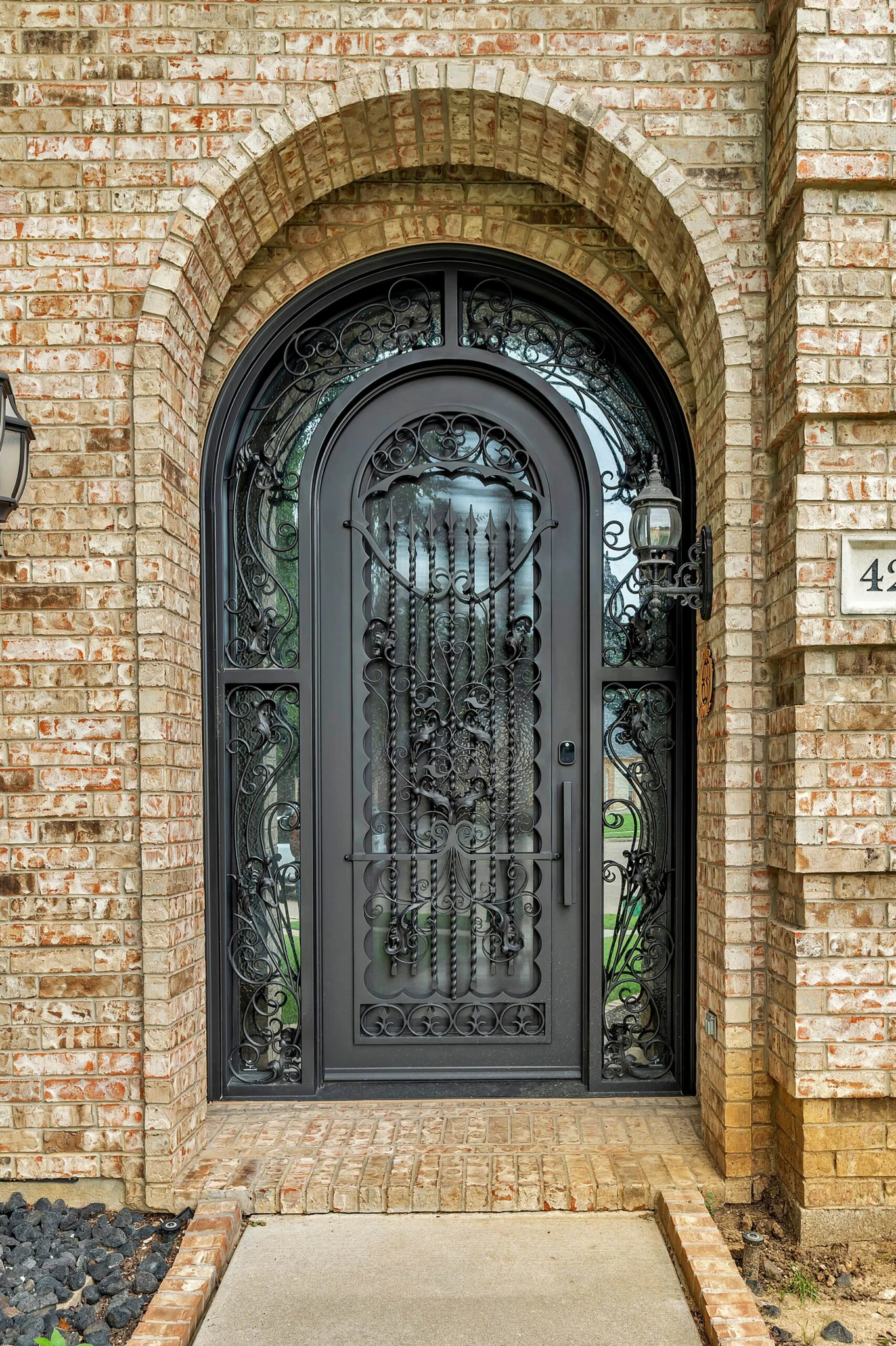 Black steel single arched entry door with scrollwork and sidelights