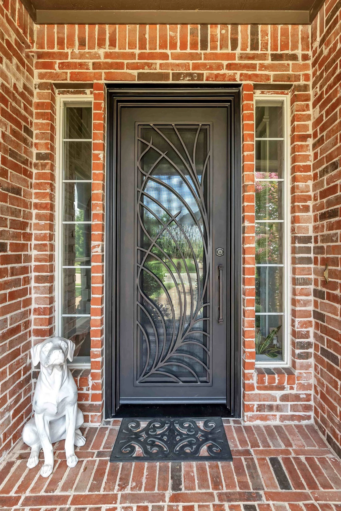 Black steel single entry door with scrollwork glass and sidelights, brick exterior