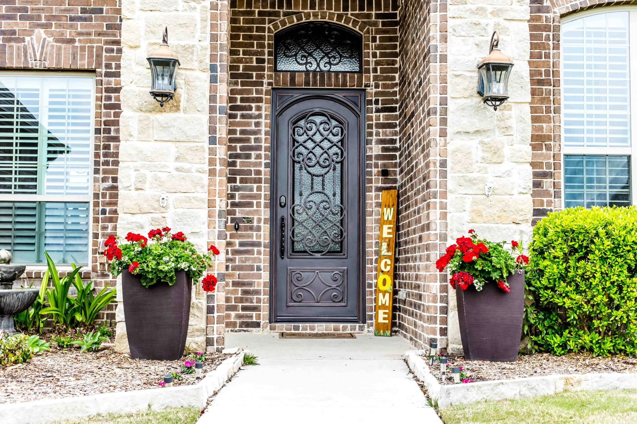 Black steel single entry door with scrollwork glass insert and decorative transom