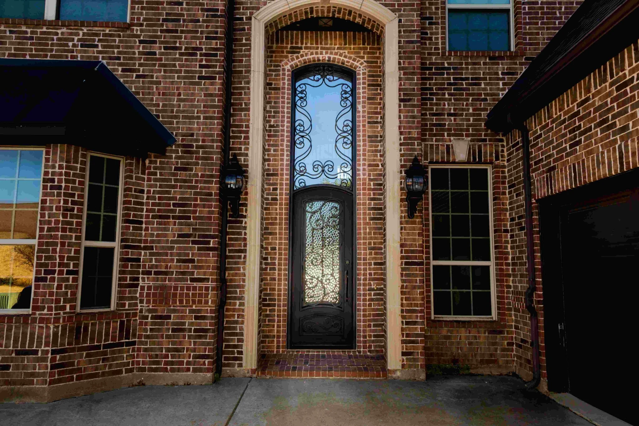 Black steel single entry door with scrollwork glass, transom and sidelights