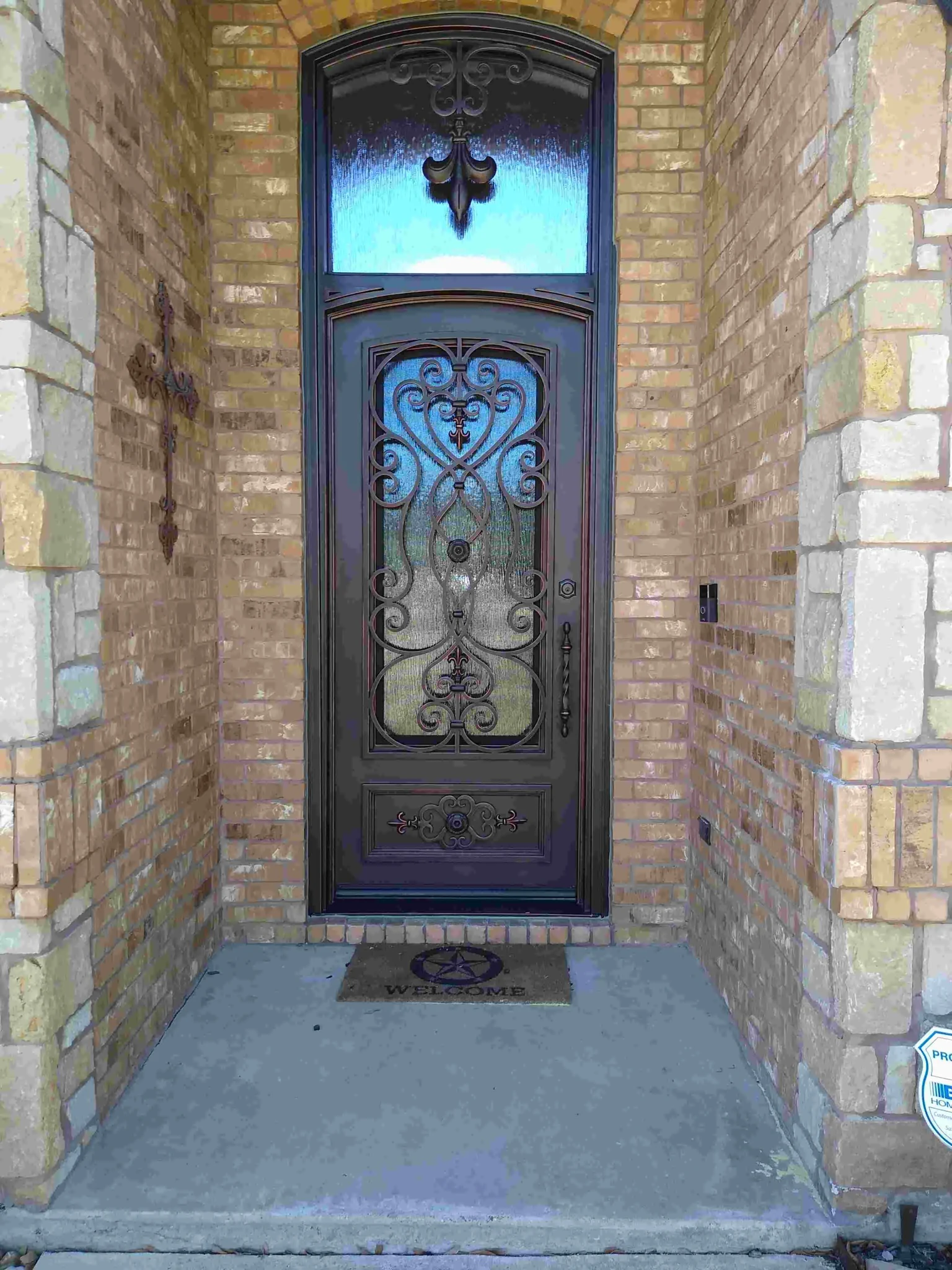 Dark bronze steel single entry door with ornate scrollwork and transom