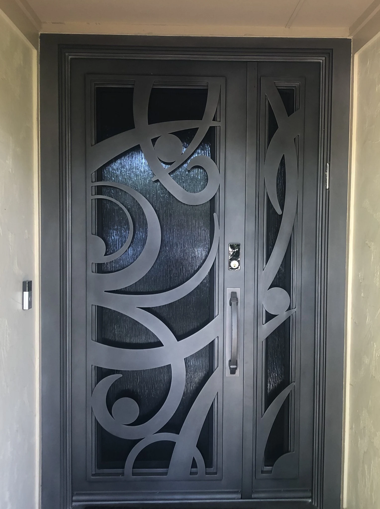 Dark steel double rectangular entry door with scrollwork glass panels
