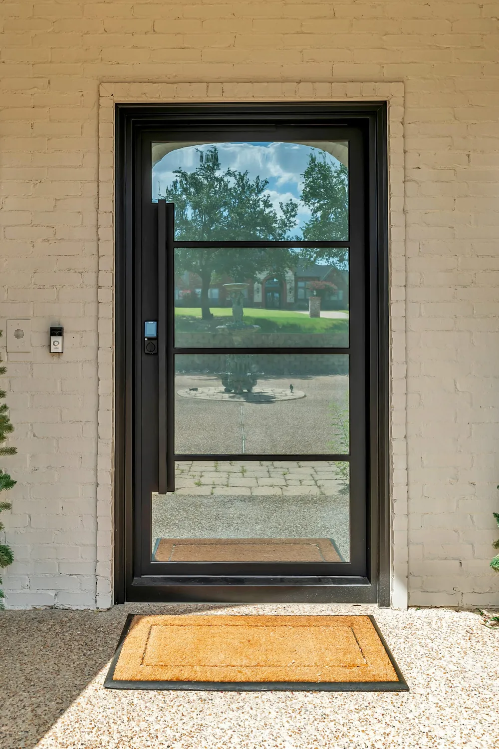 Modern single entry door with black steel frame and glass panels against brick exterior - Love That Door