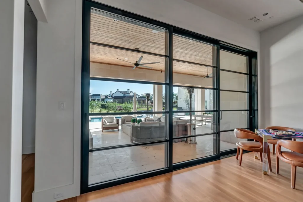 Modern black steel sliding glass doors with view to patio and pool - Love That Door