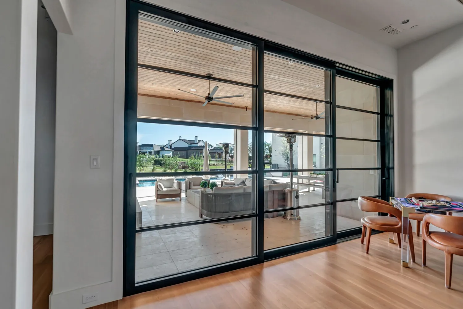 Modern black steel sliding glass doors with view to patio and pool - Love That Door