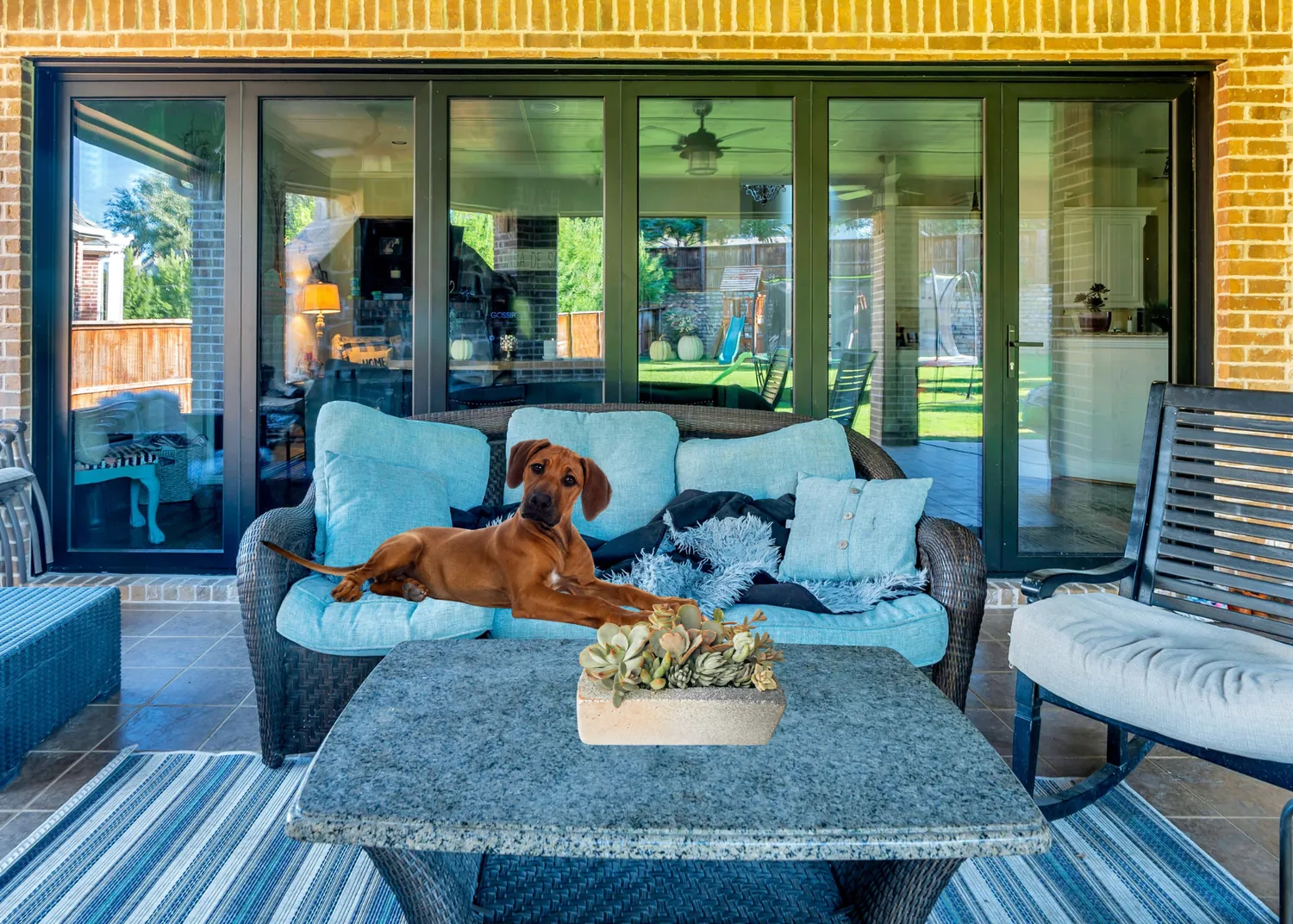 Modern outdoor living lounge with large sliding glass doors opening to a backyard - Love That Door